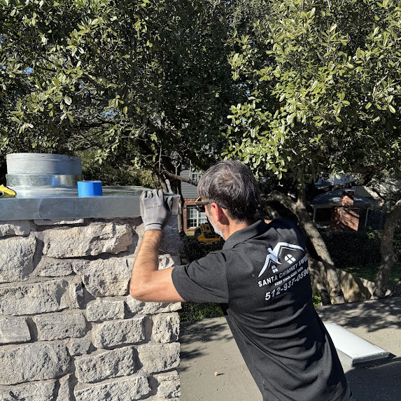 Santa Chimney Sweep technician working on a residential stone chimney