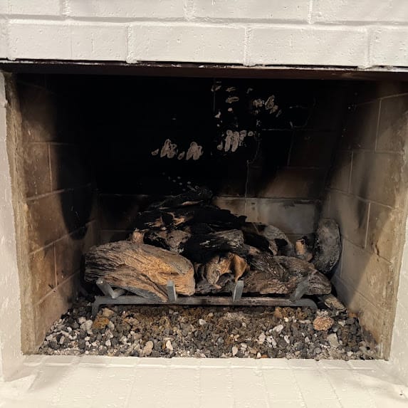 Residential fireplace showing visible damage and debris before repair