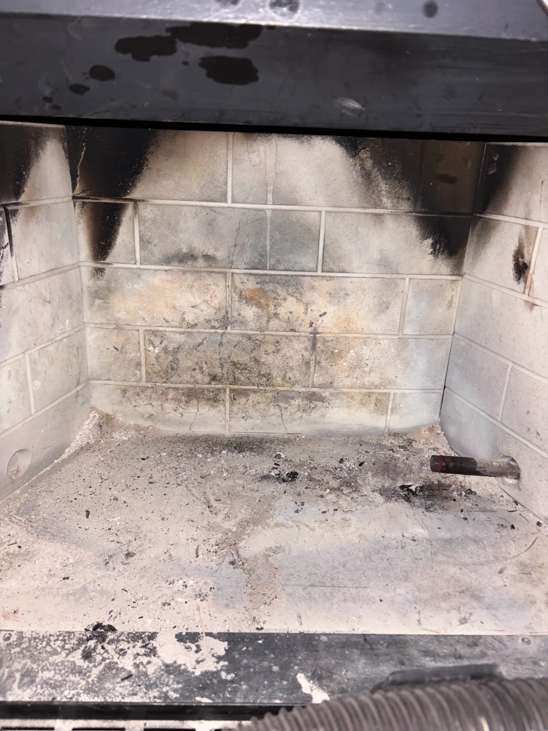Soot staining and debris inside a residential fireplace before service